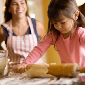 A little girl making bread with her mother.