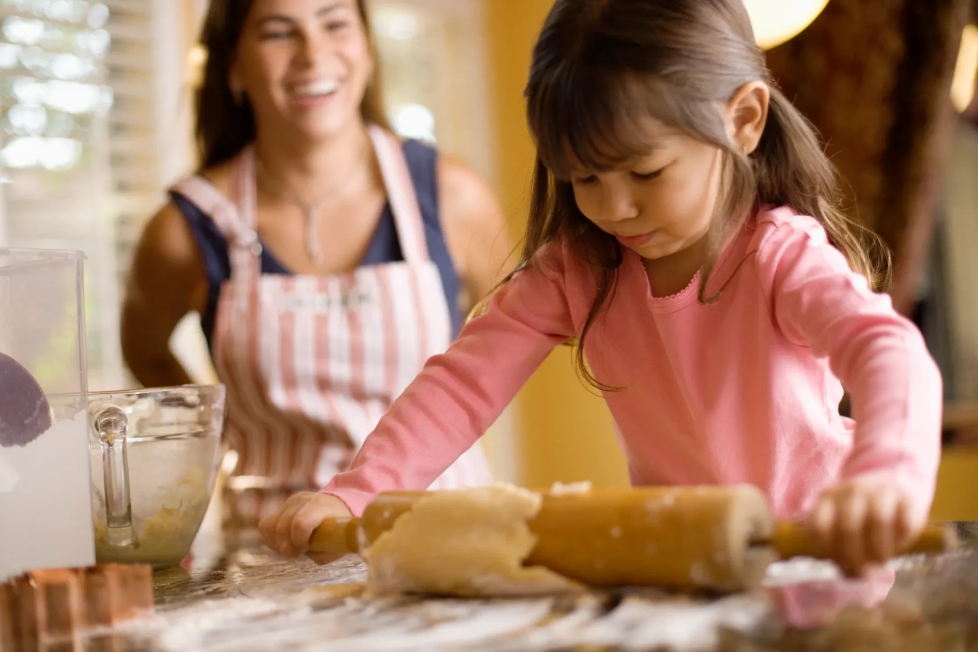 A little girl making bread with her mother.