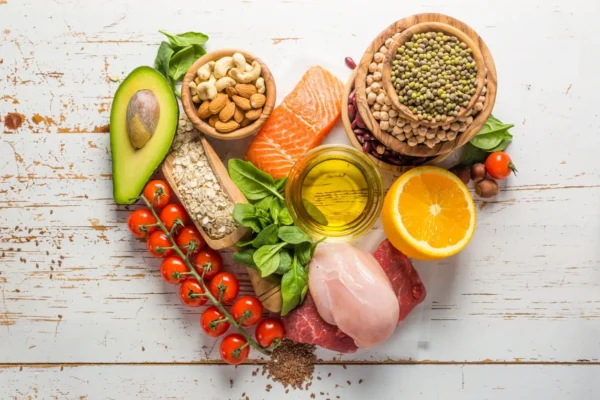 A heart shaped plate of food including meat, vegetables and nuts.