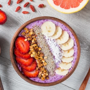 A bowl of fruit and nuts on top of the table.