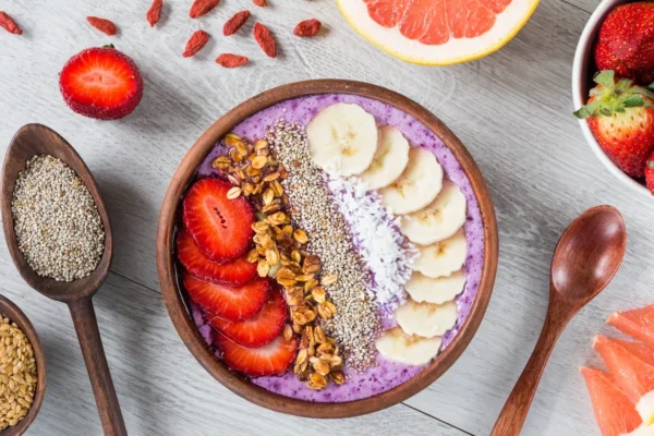 A bowl of fruit and nuts on top of the table.