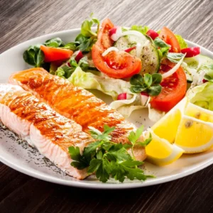 A plate of food with fish and salad on it.