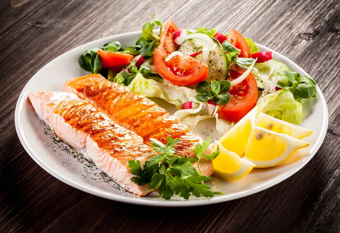 A plate of food with fish and salad on it.